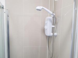 a shower with a phone in a bathroom at Kathleen House Plus in Enfield