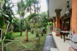 a garden with palm trees and a building at Rahayu House Ubud in Ubud