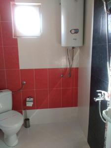 a bathroom with a toilet and a window and red tiles at Fits Guest House in Primorsko +46 photos