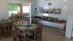 ein Esszimmer mit Tischen und Stühlen und eine Küche in der Unterkunft Hotel Maringa in Maringá