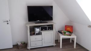 a tv on top of a white dresser with a chair at Ferienwohnung Brunnenstrasse in Bremervörde