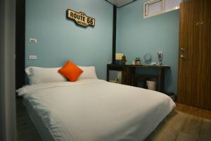 a bedroom with a white bed with an orange pillow at And B&B in Hengchun