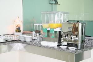 a kitchen counter with a blender and cups and plates at Hotel Soldera Inn in Sertãozinho