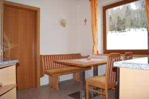 a kitchen with a table and chairs and a cross on the window at Pension Dürregger in Flattach