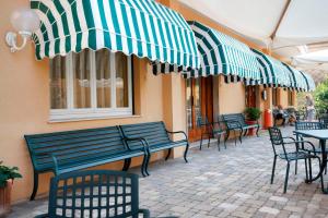 un patio al aire libre con bancos, mesas y sombrillas en Albergo Adriana, en Celle Ligure