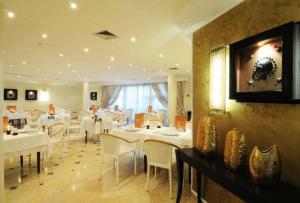 een restaurant met witte tafels en stoelen en een televisie bij Hotel du Parc in Tunis