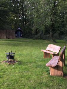 昂姆林的住宿－新奧克萊博德露營地旅館，两个木凳坐在草地上