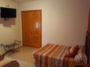 a bedroom with a bed and a wooden door at Pensión Restaurante Páramo in La Herradura