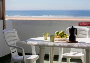 a table with a bowl of fruit on it with a view of the ocean at Apartamentos Calypso in Punta Umbría