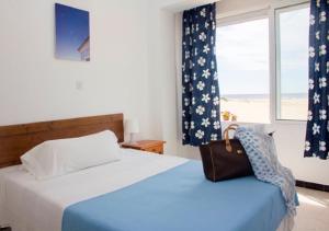a bedroom with two beds and a window and a purse at Apartamentos Calypso in Punta Umbría