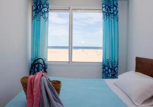 a bedroom with a bed and a window with a beach at Apartamentos Calypso in Punta Umbría
