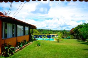 a house with a yard with a pool in the background at Pousada Recanto Do Sossego in Serra do Cipo