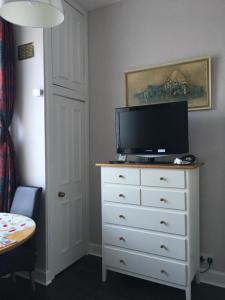 a bedroom with a dresser with a television on it at Goldenacre Private Room (Homestay) in Edinburgh