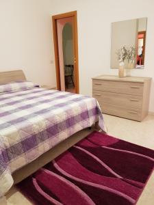 ein Schlafzimmer mit einem Bett, einer Kommode und einem lila Teppich in der Unterkunft Alla casa di Anna in Trapani