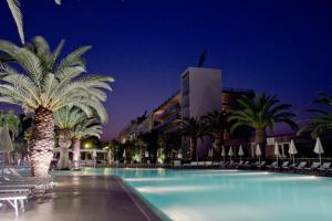 a pool with palm trees and chairs and a building at Eureka Palace Hotel Spa Resort in Cassibile