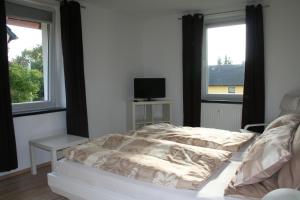 um quarto com uma cama e duas janelas em Orange Sun Apartment em Braunschweig