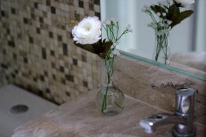 a glass vase with flowers on a counter in a bathroom at Luz Hotel in Goiânia +24 photos