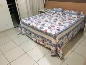 a bedroom with a bed with a floral quilt on it at Flats no Quartier e Village Apart Hotel in Três Poços