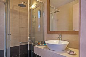 een badkamer met een wastafel en een glazen douche bij Nefeli Hotel in Platanes