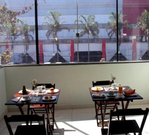 two tables with food on them in a restaurant at Luz Hotel in Goiânia