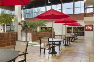 a row of tables and chairs with red umbrellas at Ramada by Wyndham Beaver Falls in Beaver Falls