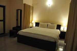 a bedroom with a large bed with two tables and two lamps at Jyothi Suites in Srīrangam