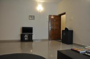 a living room with a television and a door at Jyothi Suites in Srīrangam