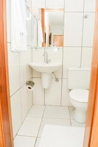 a white bathroom with a sink and a toilet at Hotel São Francisco in Ubiratã