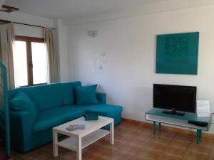 een woonkamer met een blauwe bank en een tv bij Casa Vacanze Tiffany in Corralejo