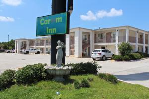 un letrero verde de la calle en un poste con una estatua en Carom Inn a Travelodge by Wyndham Denham Springs-Baton Rouge en Denham Springs