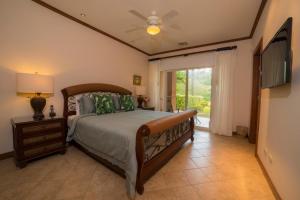 a bedroom with a bed with a ceiling fan and a television at Veranda 8F 2 bdr Garden View in Los Suenos in Herradura +38 photos