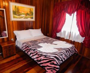 Bett in einem Zimmer mit roten Vorhängen und einem Fenster in der Unterkunft Chale Bosque da Serra - Lindo Chalé in Canela