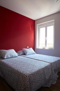 1 dormitorio con cama y pared roja en Casa de Polentinos, en Ávila