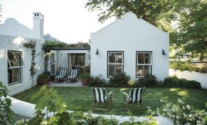 a white house with chairs in the yard at Vredenhof Farm Cottage in Elgin