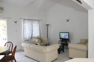 ein Wohnzimmer mit weißen Möbeln und einem TV in der Unterkunft Dreambeach Holiday in Flic-en-Flac