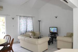 a living room with white furniture and a tv at Le Dattier -dreambeach in Flic-en-Flac