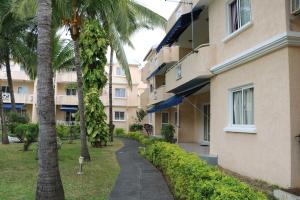a walkway next to a building with palm trees at Le Dattier -dreambeach in Flic-en-Flac
