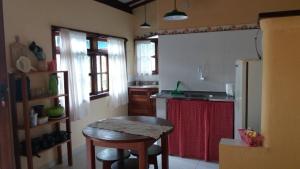 a kitchen with a table and a kitchen with a refrigerator at Hóspedes da Terra Pousada & Chalés in Arraial d'Ajuda