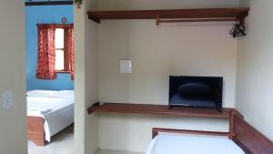 1 dormitorio con 1 cama y TV en la pared en Hóspedes da Terra Pousada & Chalés, en Arraial d'Ajuda
