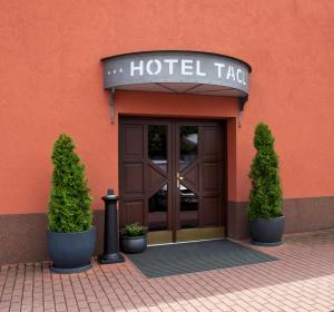 ein Taco des Hotels mit zwei Topfbäumen davor in der Unterkunft Hotel Tacl in Holešov