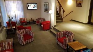 a waiting room with red chairs and a tv at Hotel Kapenke in El Calafate