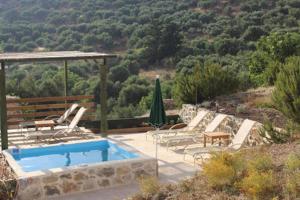 una piscina con sedie, tavolo e ombrellone di House in Organic Orgon farm a Apóstoloi