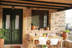 a patio with a green door and a table and chairs at House in Organic Orgon farm in Apóstoloi