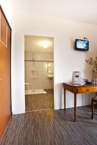 a room with a bathroom with a shower and a desk at Auberge Obersolberg in Eschbach-au-Val