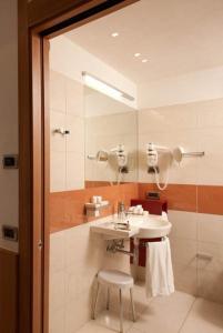 a bathroom with a sink and a shower and a stool at Hotel Alaska Cortina in Cortina dʼAmpezzo