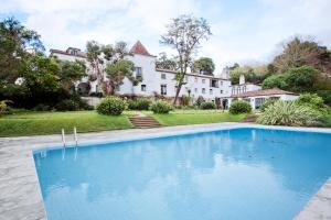 una gran piscina azul frente a una casa en Quinta de Sao Thiago, en Sintra