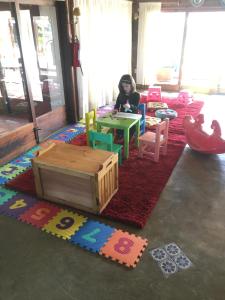 un niño sentado en una mesa en una habitación con juguetes en Pueblo Chico Agroturismo Hotel, en La Floresta