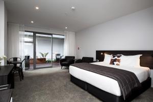 a bedroom with a large bed and a living room at The Metrotel in New Plymouth