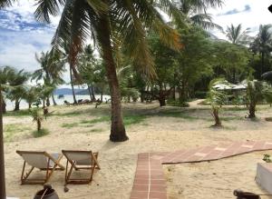 two chairs and a palm tree on the beach at Peppercorn Beach Resort in Phú Quốc