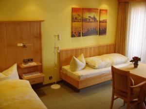 a bedroom with two beds and a table and a desk at Gästehaus zur Färbe Apartments in Oberstdorf